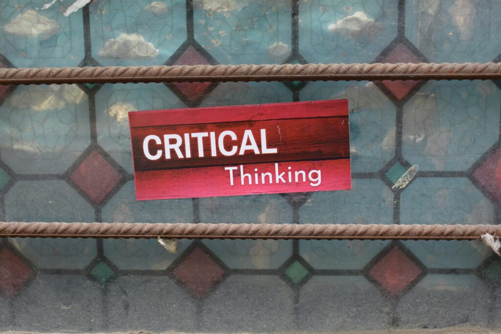 Pink critical Thinking sticker overlaying stained glass window.