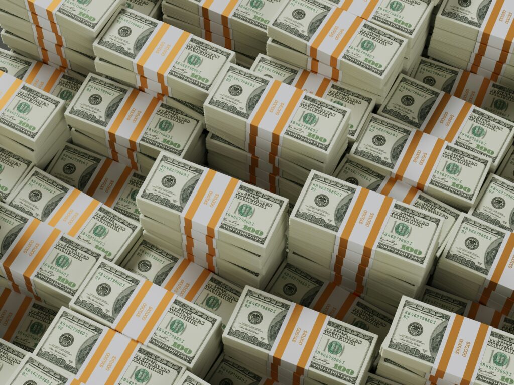 Stacks of bundled U.S. one-hundred-dollar bills arranged in rows, representing large sums of money or massive financial investment.